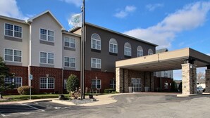 A multi-story building with a covered entrance and a flagpole with an American flag.