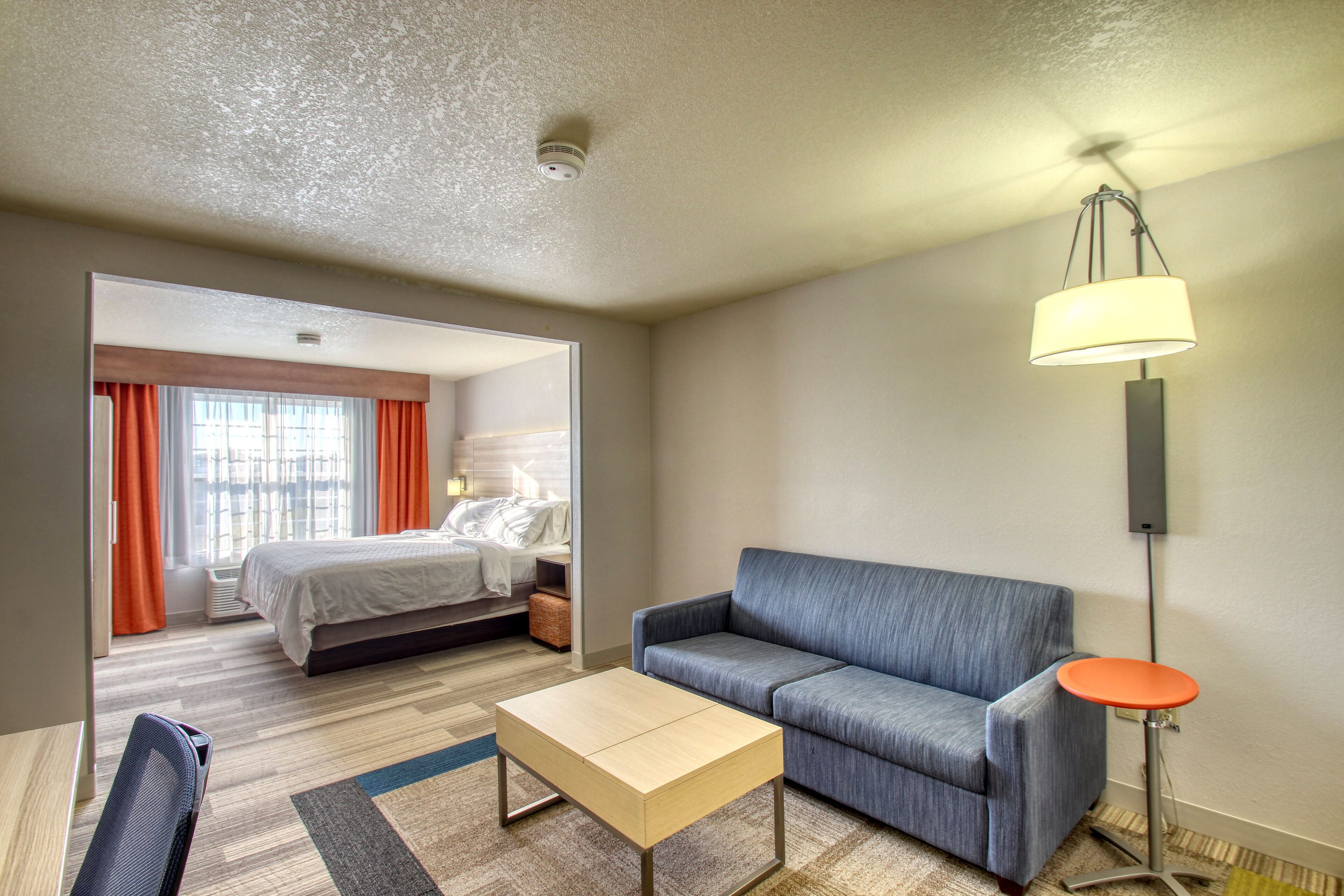 A hotel room with a bed, a sofa, a coffee table, and a lamp.