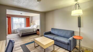 A hotel room with a bed, a sofa, a coffee table, and a lamp.
