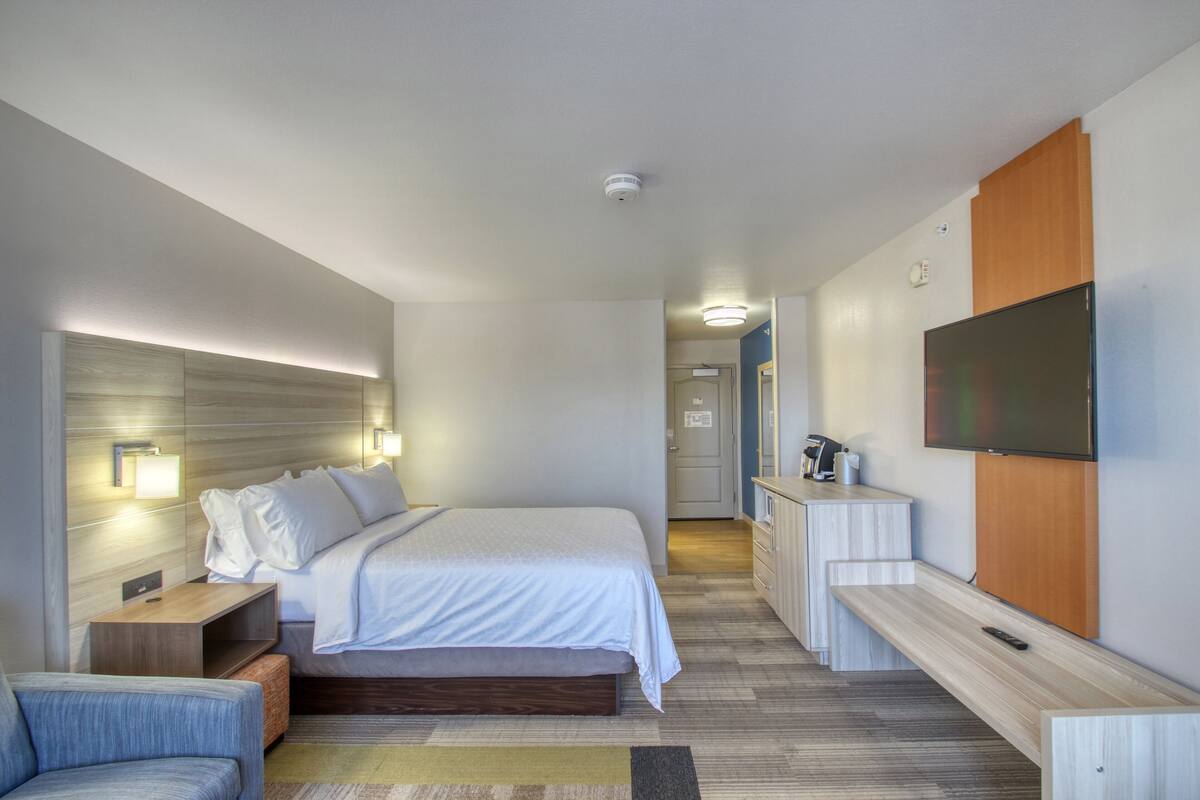 Ein modernes Hotelzimmer mit einem großen Bett, Nachttischen, einem Fernseher und einer Sitzecke.