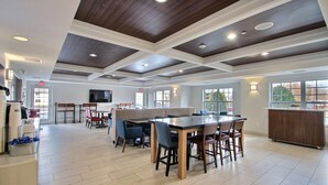 A spacious indoor area with a large wooden table and chairs, a buffet counter, and a reception desk.