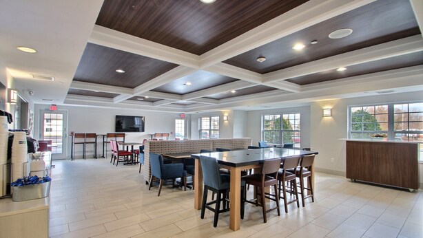 Un espacio interior amplio con una gran mesa de madera y sillas, un mostrador de buffet y un mostrador de recepción.