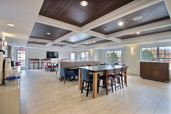 A spacious indoor area with a large wooden table and chairs, a buffet counter, and a reception desk.