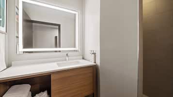 A modern bathroom with a white sink, a large mirror, and wooden cabinetry.