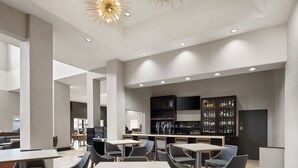 A modern interior with high ceilings, recessed lighting, and a bar area with shelves of bottles. - Holiday Inn & Suites Albuquerque Airport by IHG (Albuquerque)