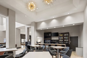 Un interior moderno con techos altos, iluminación empotrada y una zona de bar con estantes llenos de botellas.