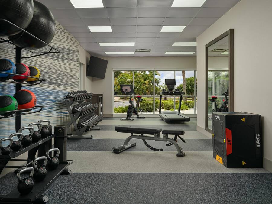 Ein Fitnessstudio mit Kettlebells, Kurzhanteln, einer Bank und Trainingsgeräten.