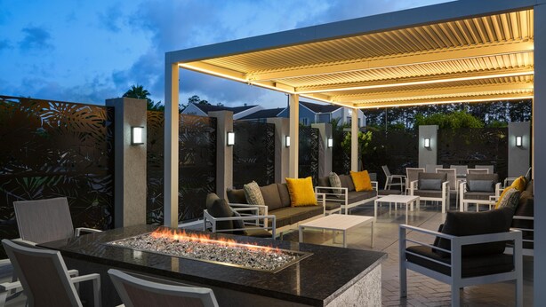 An outdoor patio with a fire feature, seating, and ambient lighting. - DoubleTree by Hilton Brunswick (Brunswick)
