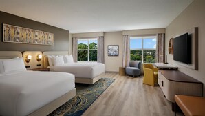 A hotel room with two beds, a desk, a chair, a TV, and large windows. - DoubleTree by Hilton Brunswick (Brunswick)