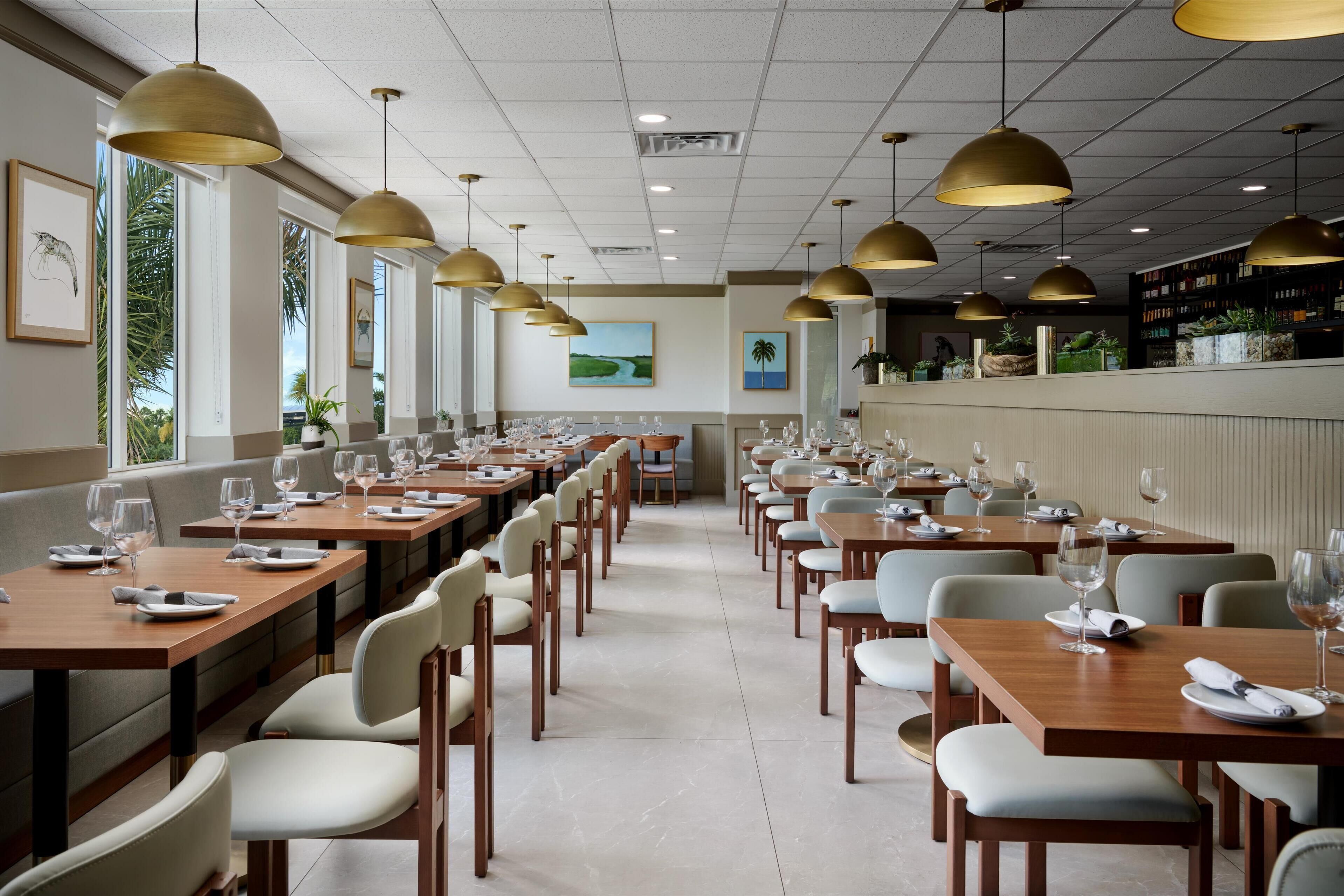 Un restaurante con mesas largas, sillas y lámparas colgantes.