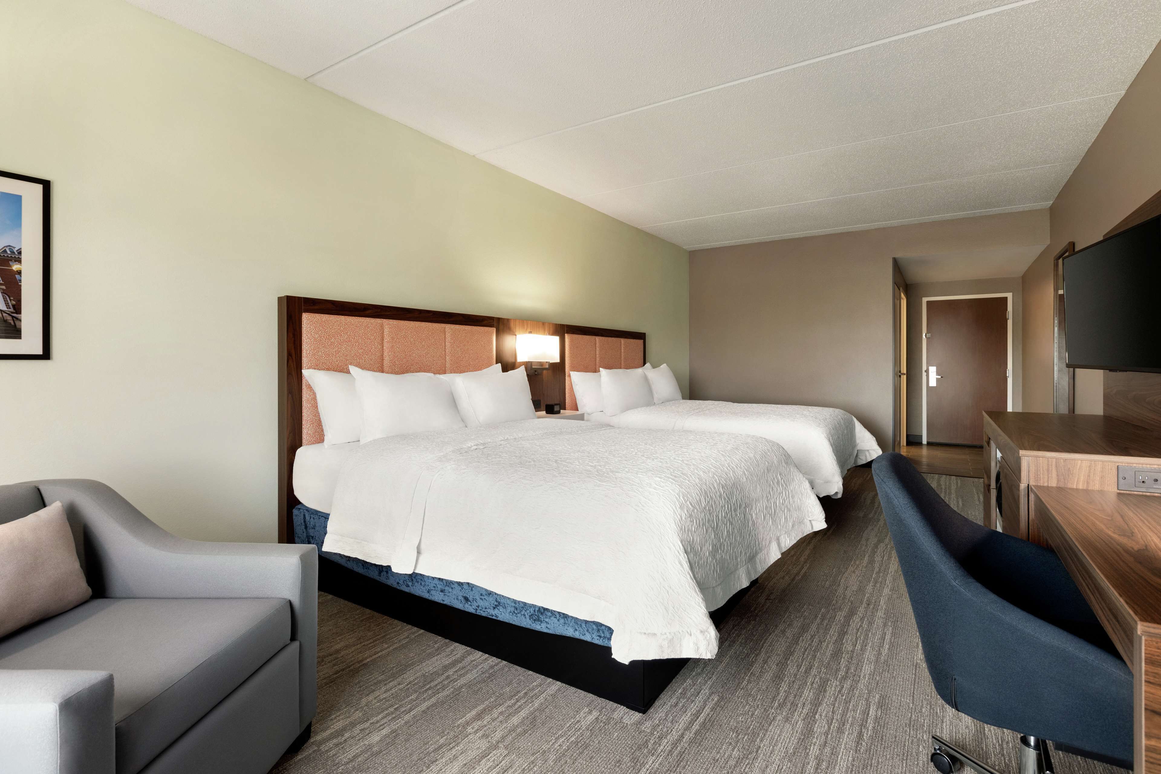 A hotel room with a large bed, two bedside tables, a desk, and a chair.