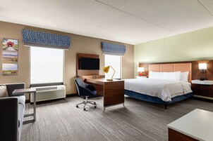 Una habitación de hotel con cama, escritorio, silla y televisor.