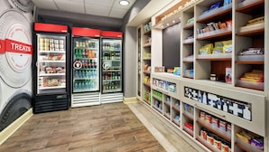 A store interior with refrigerated treat cases, shelves stocked with snacks, and a section for personal items. - Hampton Inn & Suites Frederick-Fort Detrick (Frederick)