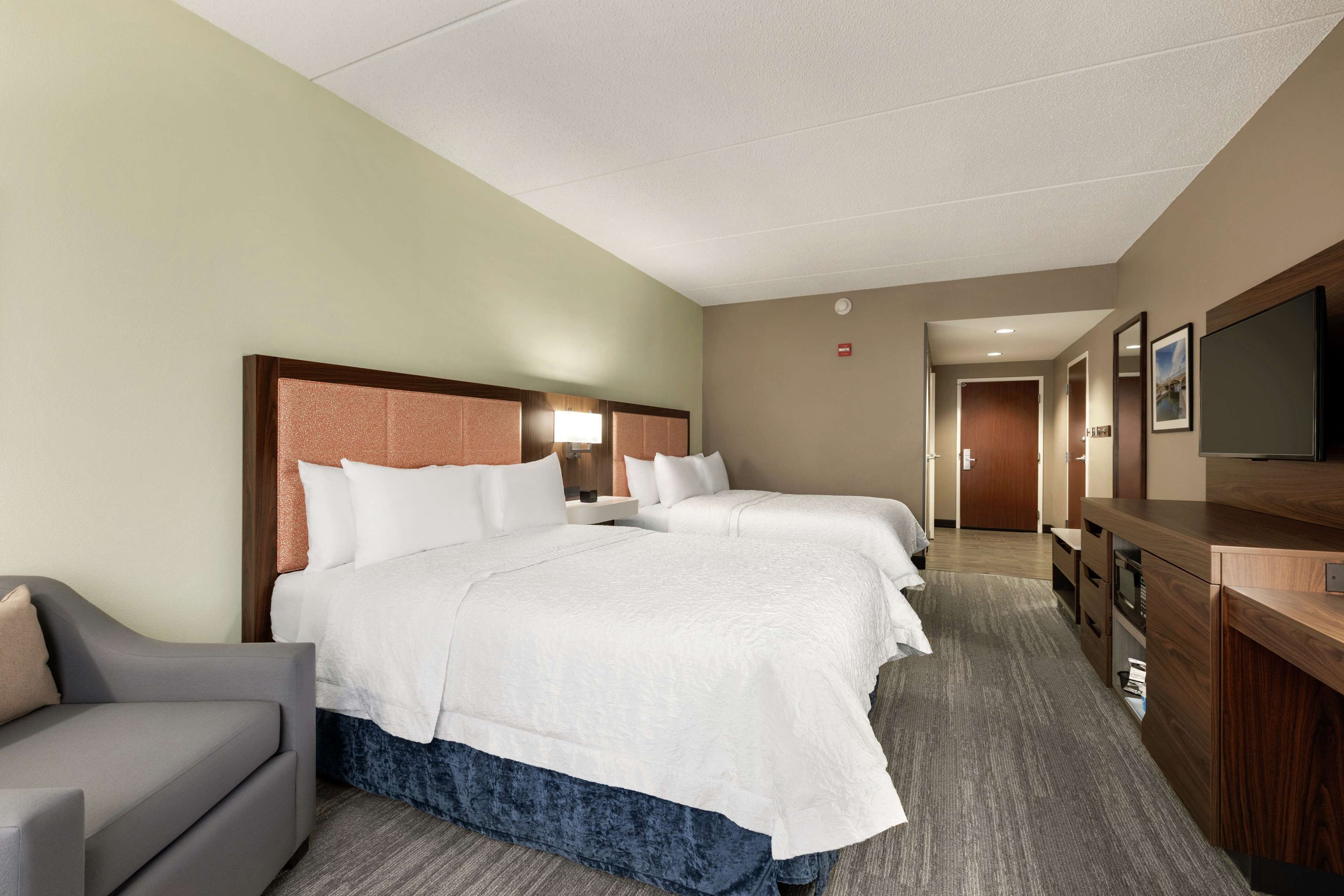 A hotel room with a large bed, a desk, a TV, and a sofa.