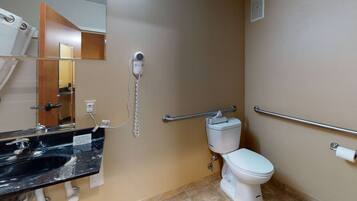 A bathroom with a black sink, a white toilet, a mirror, and a hand dryer.