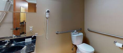 A bathroom with a black sink, a white toilet, a mirror, and a hand dryer.