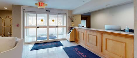 A reception area with a glass door entrance, a reception desk, and a seating area with a couch.