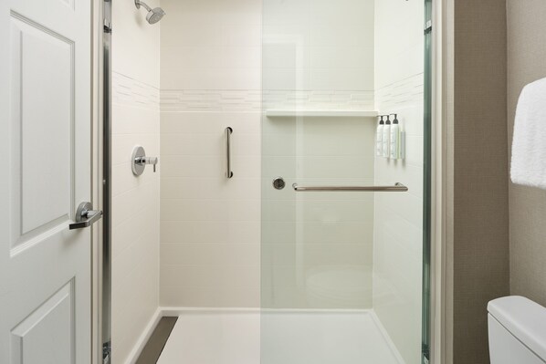 A modern bathroom with a glass shower enclosure, a white door, and a glass partition.