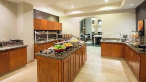 Una cocina moderna con encimeras de granito, armarios de madera y una isla central con productos alimenticios.