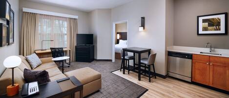 Una habitación de hotel moderna con sala de estar, comedor y kitchenette.