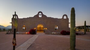 A historic building with arched entrances and a bell tower, surrounded by cacti and desert landscaping. - Wekopa Casino Resort (Fort McDowell)