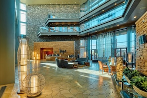 A spacious lobby with a stone wall, a fireplace, and a seating area with a sofa and chairs.