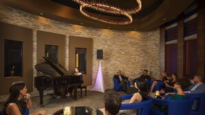 A lounge area with a grand piano, blue seating, and a stone wall. - Wekopa Casino Resort (Fort McDowell)