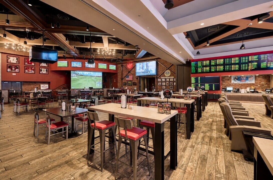 Eine Sportsbar mit mehreren Bildschirmen, einer Bar und einem Holzboden.