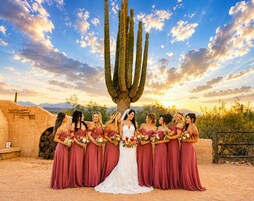 Un grupo de personas de pie frente a un cactus grande con un paisaje desértico al fondo.