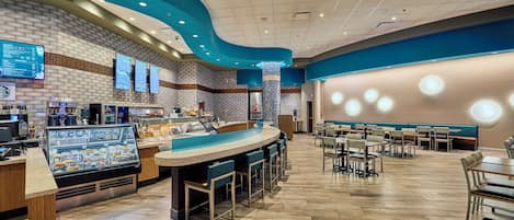 A modern restaurant with a bar area, seating, and a menu display.