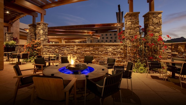 An outdoor patio area with stone pillars, a fire pit, and seating arrangements. - Wekopa Casino Resort (Fort McDowell)