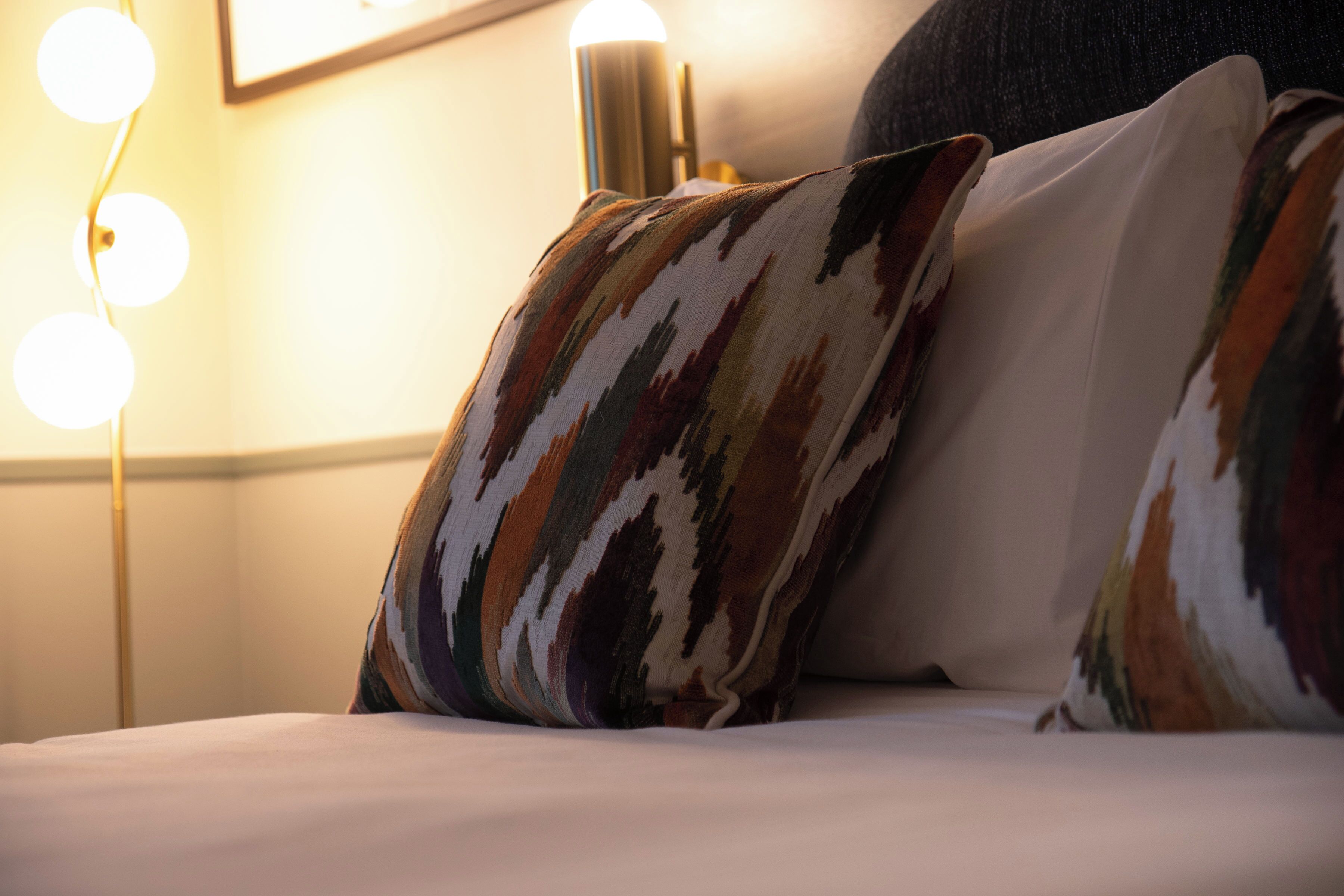 A bed with patterned pillows and a bedside lamp.