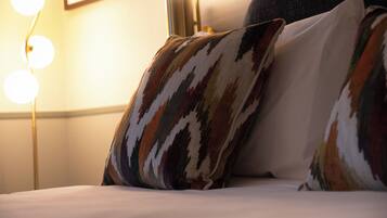 A bed with patterned pillows and a bedside lamp.