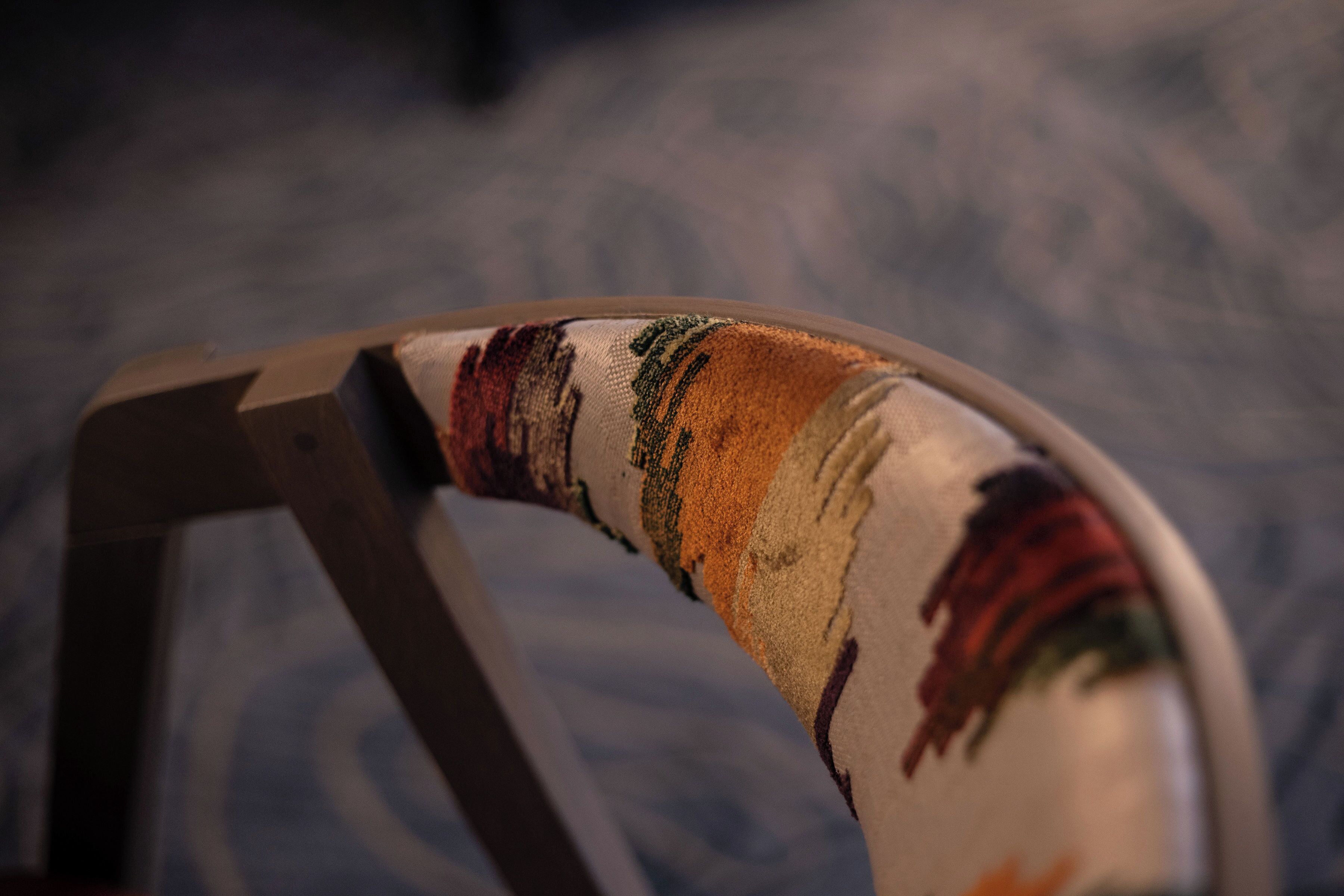A curved, upholstered chair with a patterned fabric.