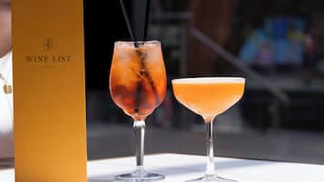 Two cocktails on a table with a wine list box in the background.