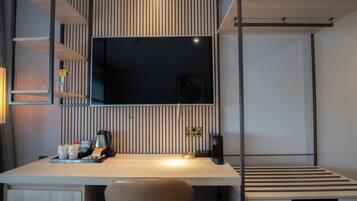 Una camera moderna con una scrivania in legno, una televisione a parete e un letto con una testiera a righe.