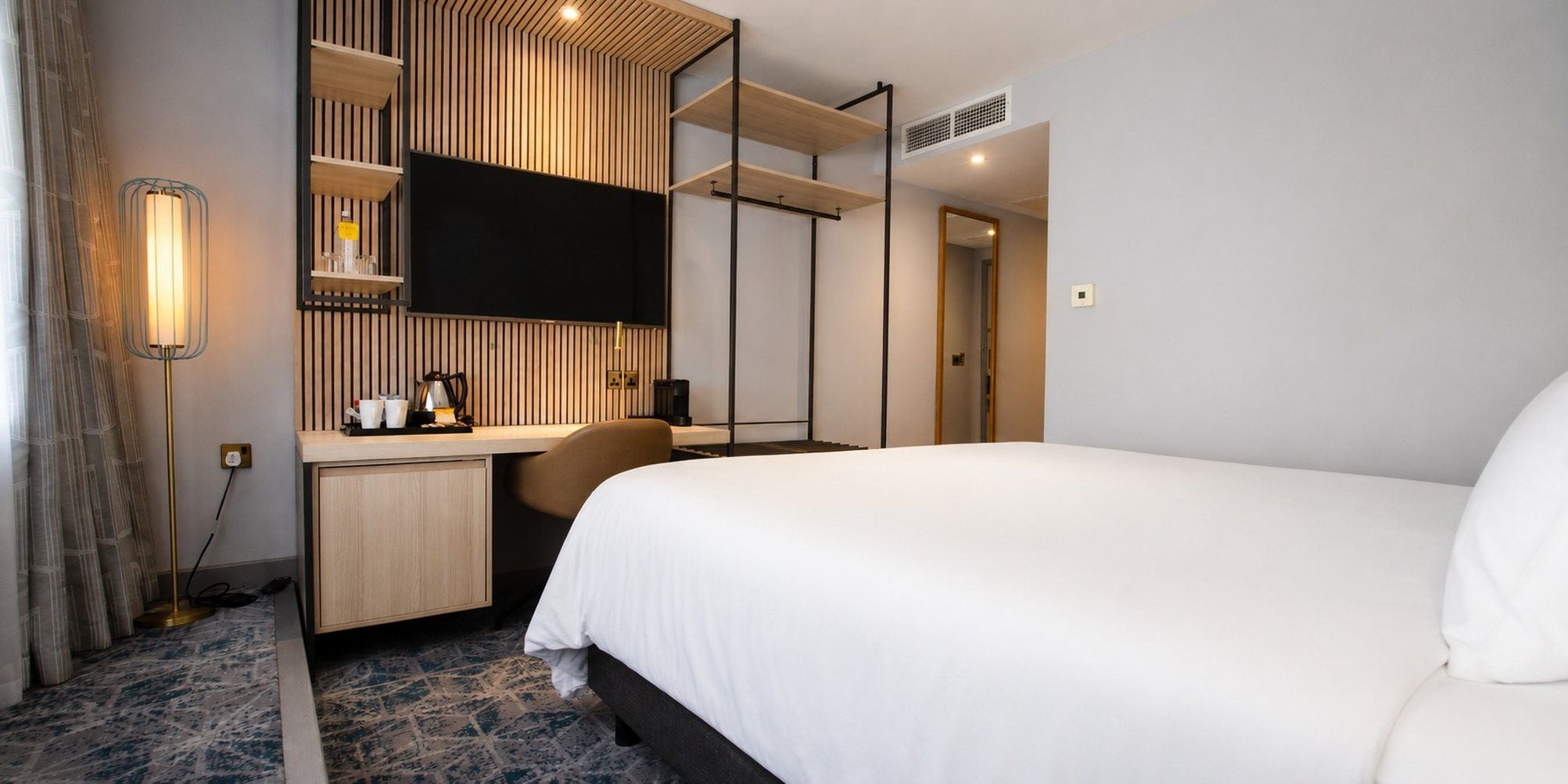 Una habitación de hotel con cama, escritorio, televisor de pantalla plana y armario.
