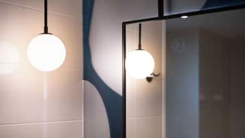 A bathroom with two round pendant lights, a mirror, and a tiled wall.