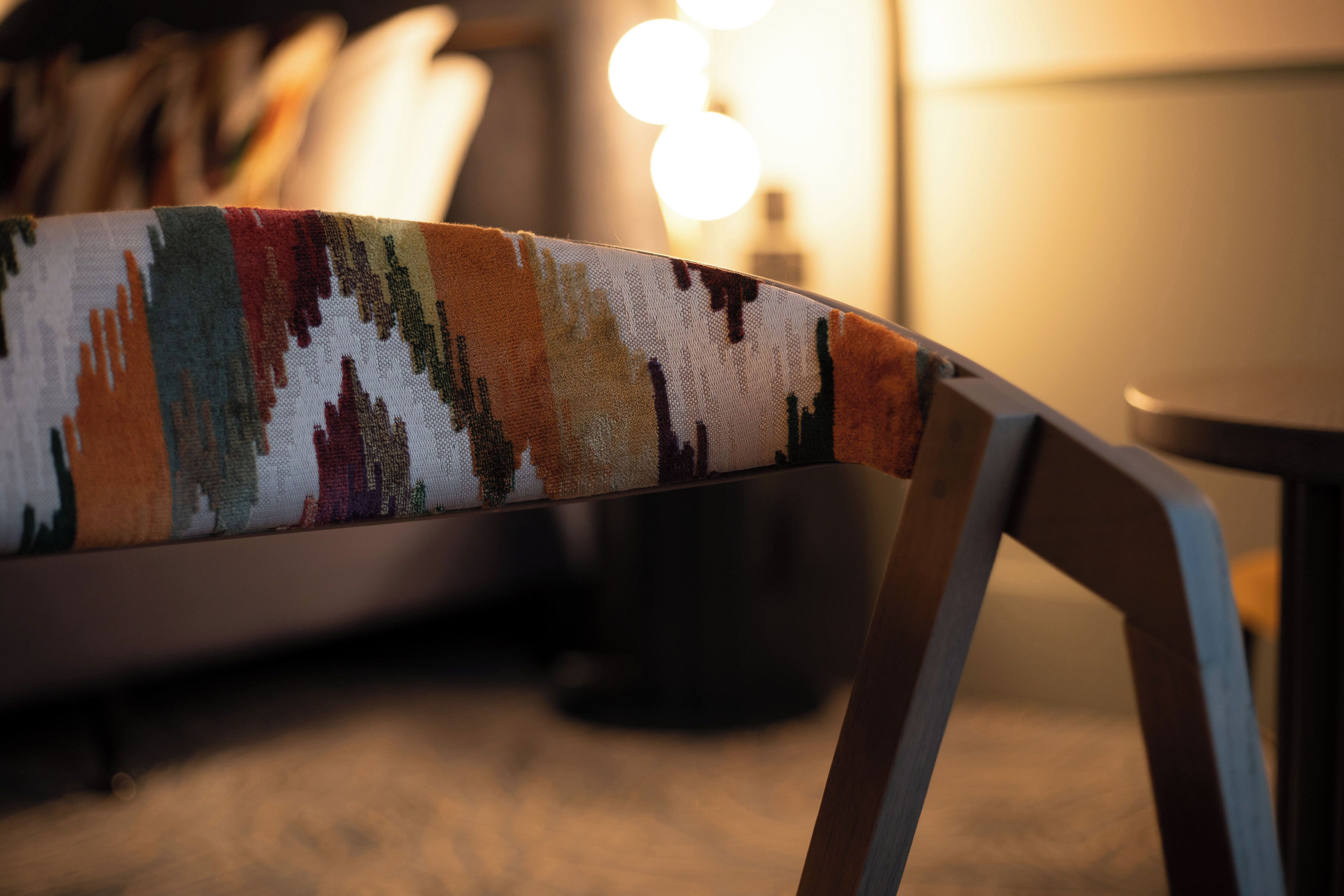 A chair with a colorful woven backrest.
