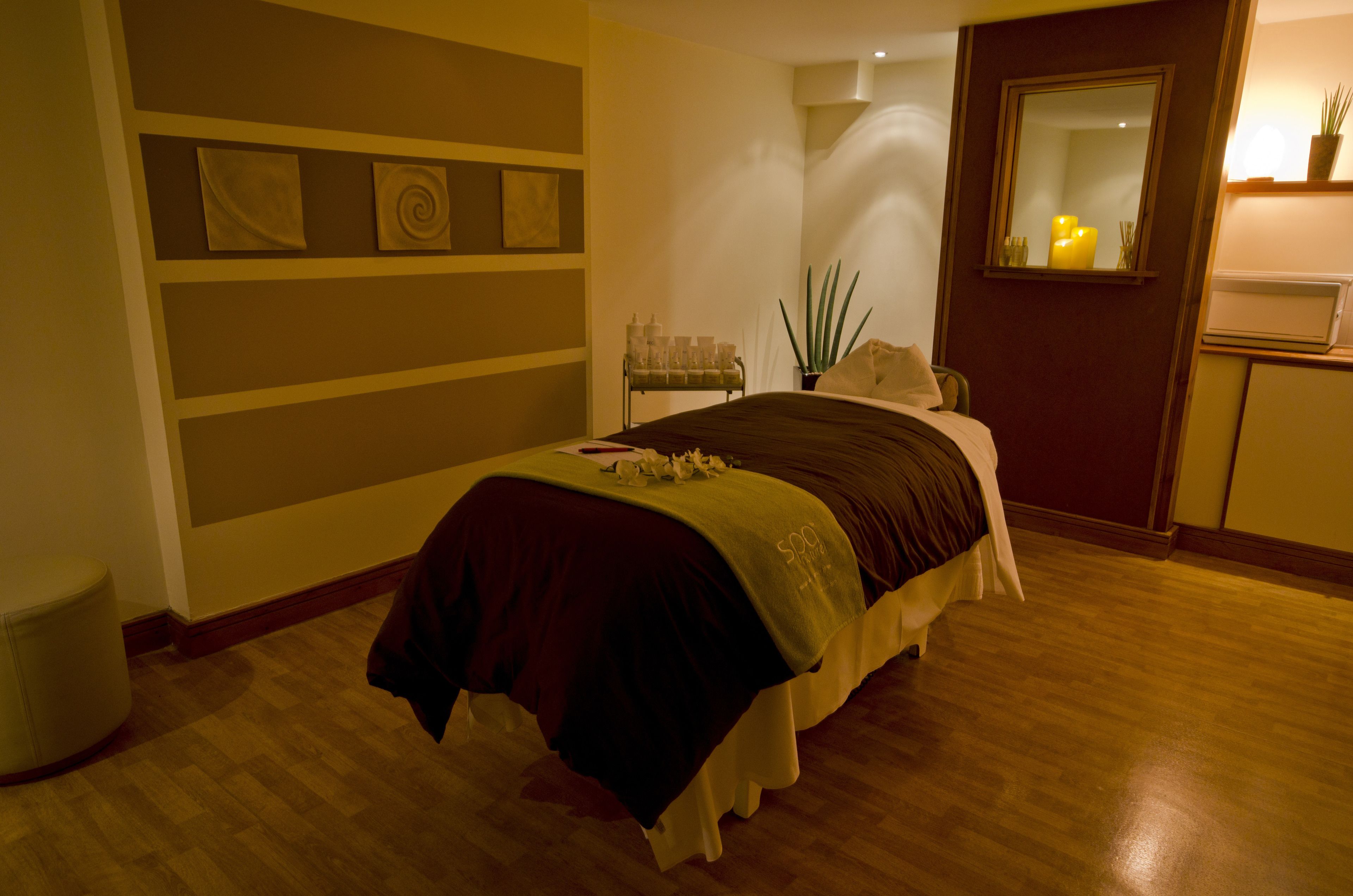 A neatly arranged bedroom with a bed, bedside table, and a mirror.
