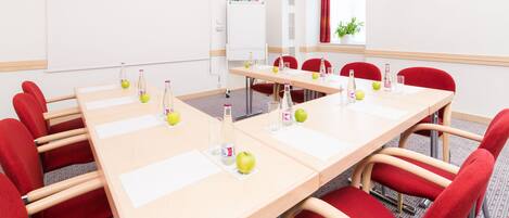 A conference room with a long table, red chairs, and a whiteboard.