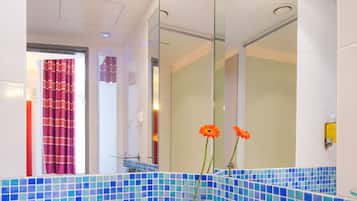 A bathroom with a large mirror, a sink, and blue-tiled walls.