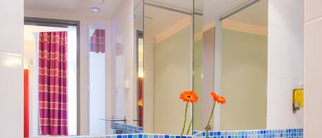 A bathroom with a large mirror, a sink, and blue-tiled walls.