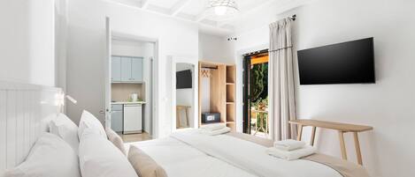A modern bedroom with a large bed, a TV mounted on the wall, and a view of the outdoors.