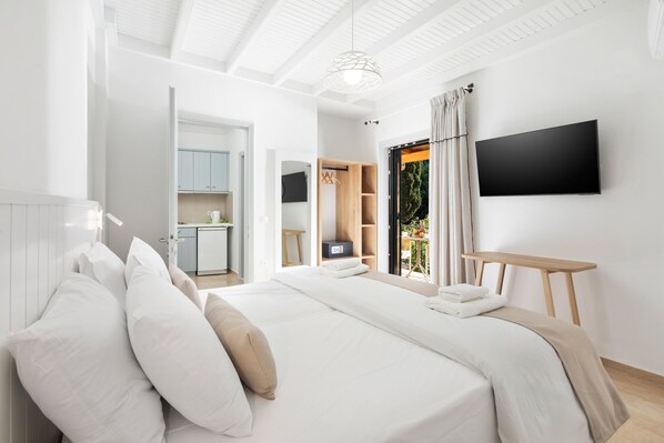 A modern bedroom with a large bed, a TV mounted on the wall, and a view of the outdoors. - Bella Vista Beach Hotel and Studios (Corfu)