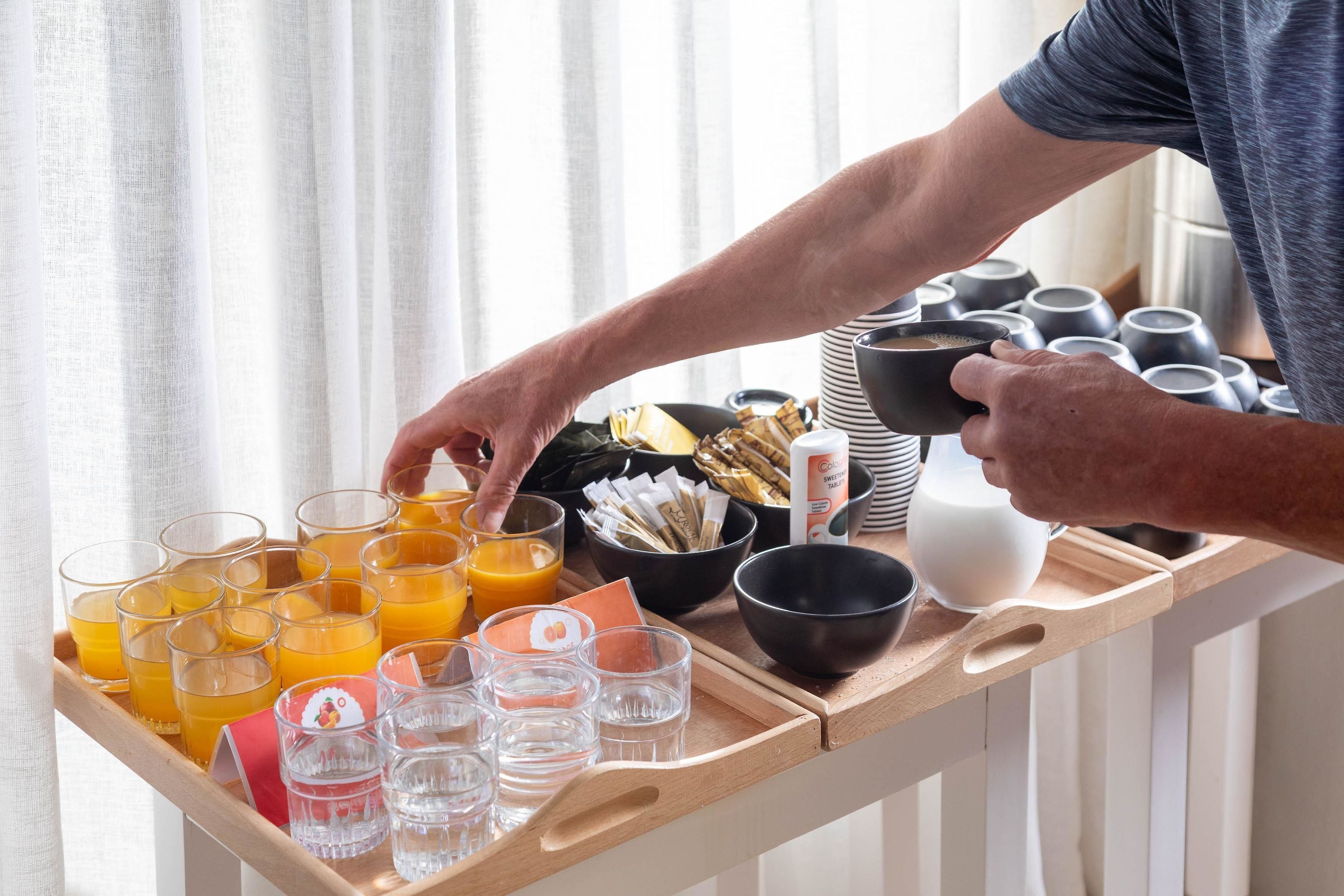 Un vassoio per la colazione con succo d'arancia, caffè e diversi prodotti per la prima colazione.