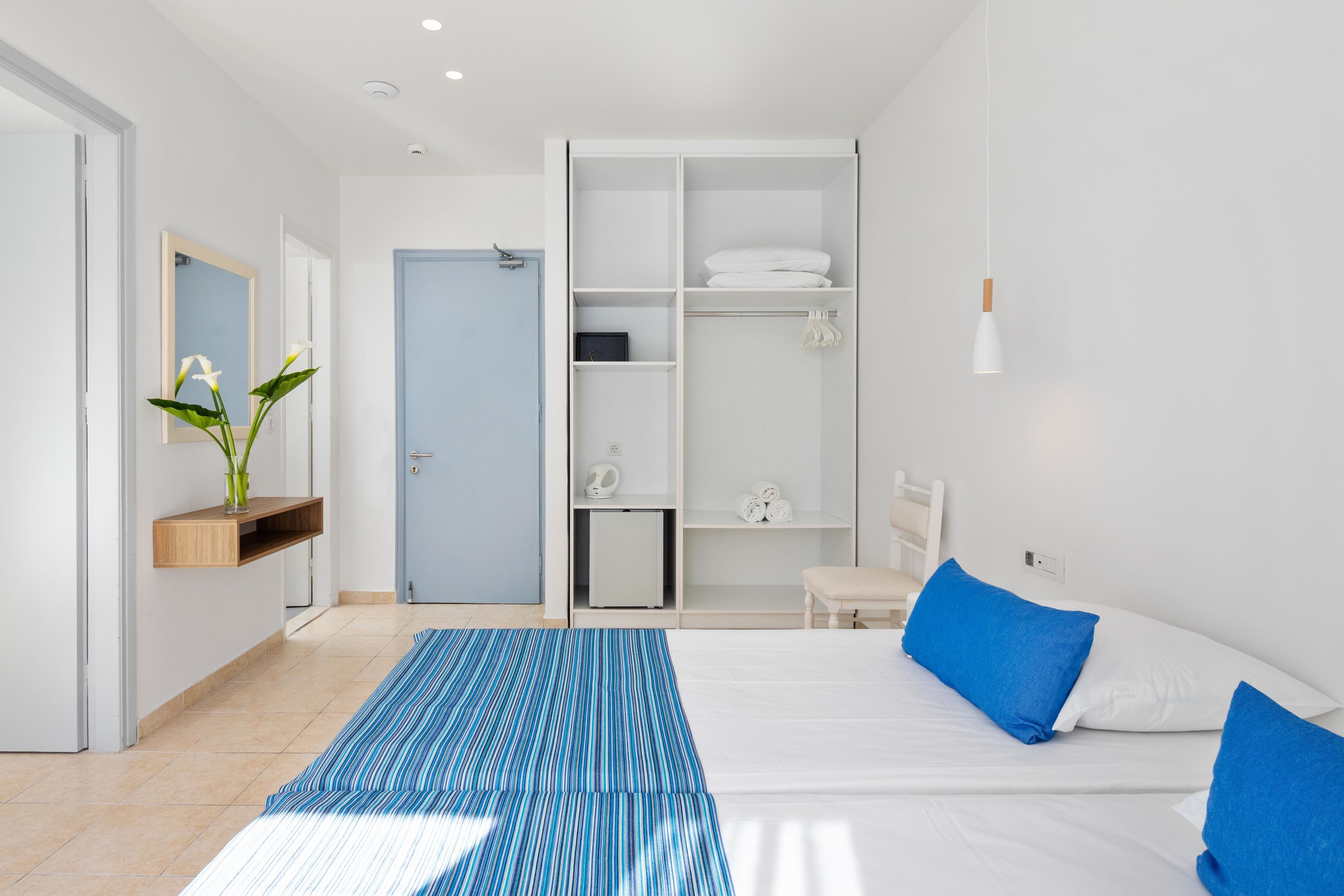 A modern bedroom with a bed, a wardrobe, a bedside table, and a blue-striped area rug.