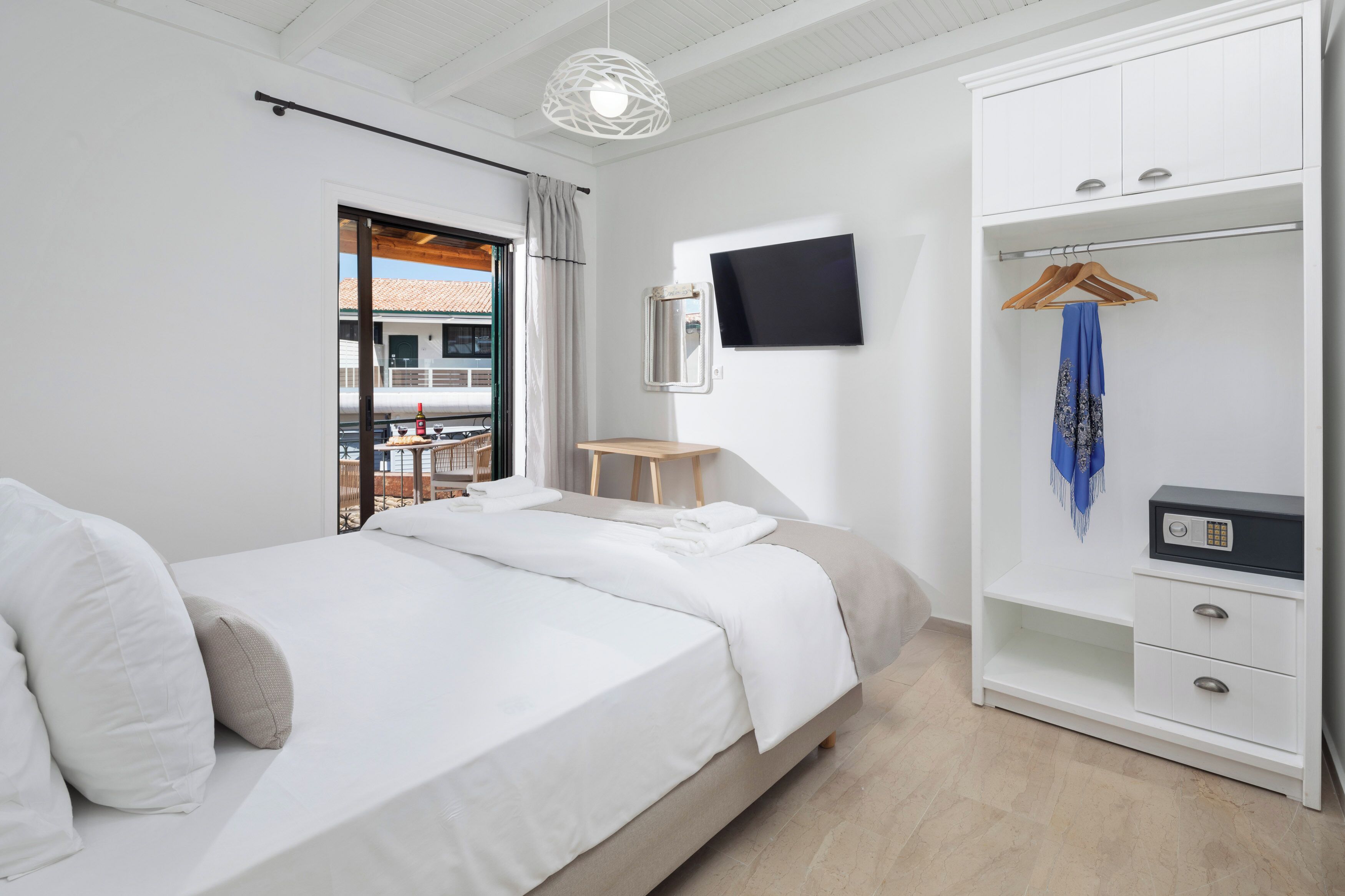 Un dormitorio moderno con cama, televisor, armario y escritorio.