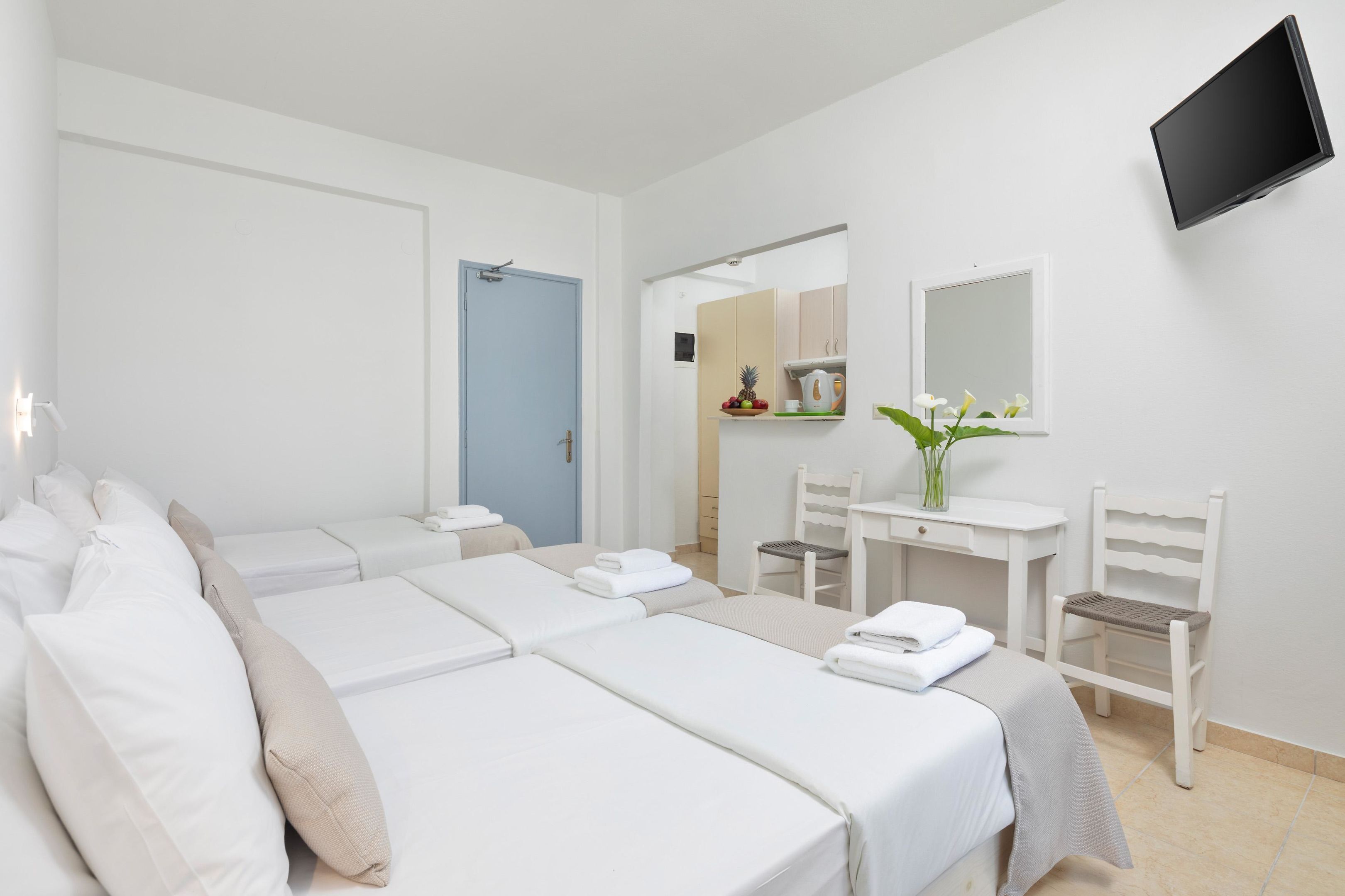 Ein Hotelzimmer mit zwei Betten, einem Schreibtisch, einem Stuhl, einem Fernseher und einer Badezimmertür.