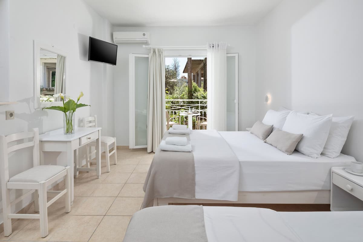 Une chambre d’hôtel comprenant un lit, un bureau, une chaise, une télévision et un balcon avec une table et des chaises.
